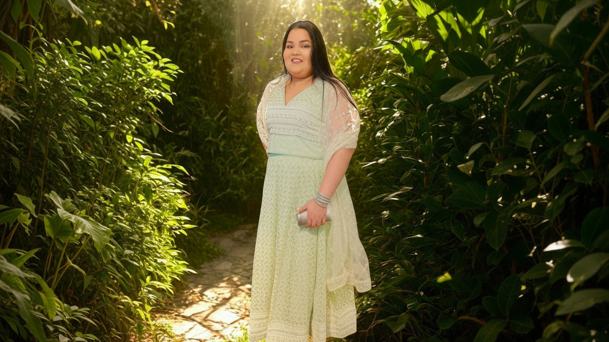 Woman in a light green dress standing in a sunlit forest