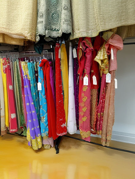 Colorful traditional garments hanging on a rack with tags.